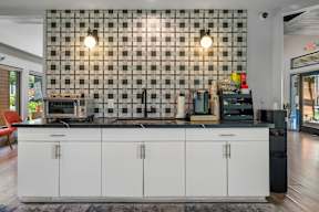 A kitchen with white cabinets and a black and white checkered backsplash.