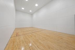 A squash court with wooden flooring and white walls.