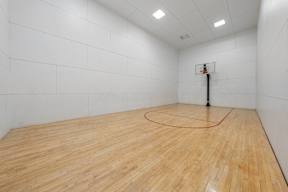 A basketball court with a wooden floor and a basketball hoop.