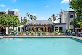 A swimming pool in front of a house with a fence around it.