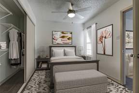 A bedroom with a bed, a bench, and a painting on the wall.