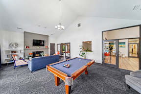 A pool table is in the middle of a room with a couch and a fireplace.