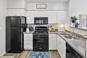 A kitchen with black appliances and white cabinets.