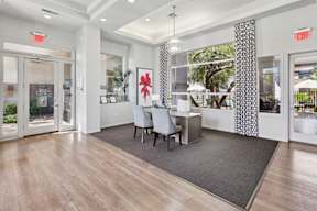 A room with a grey chair and a grey rug in front of a desk.