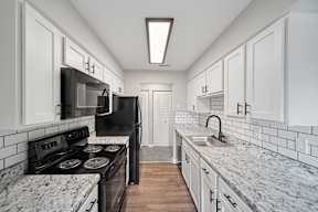 A kitchen with black appliances and white cabinets.