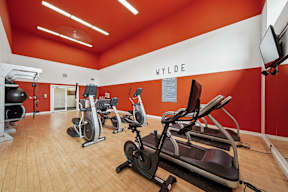 A gym with a row of exercise bikes and a television.