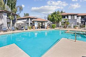 A swimming pool in a residential area with houses and trees in the background.