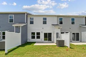 A grey house with a white fence and two air conditioning units.