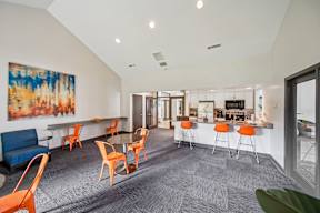 A room with a grey carpet and orange chairs.