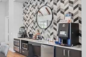 A coffee bar with a black and white chevron wallpaper and a coffee machine on the counter.