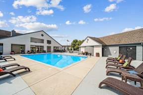 A swimming pool surrounded by sun loungers and a building in the background.