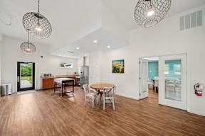 A modern open plan living and dining room with wooden floors and white walls.