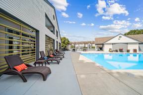 A row of sun loungers are on the left of a small pool.