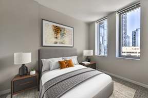 A bedroom with a large bed, a nightstand with a lamp, and a framed artwork on the wall.