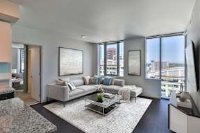A modern living room with a grey sofa and a glass coffee table.