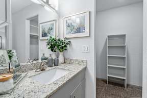 A bathroom with a sink, mirror, and shelves.