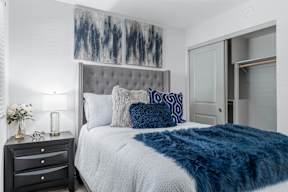 A bedroom with a bed, nightstand, and a painting on the wall.