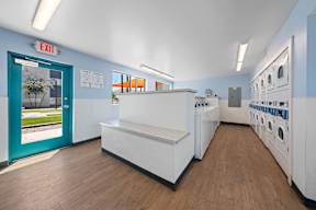 A laundromat with a blue door and a washer and dryer.