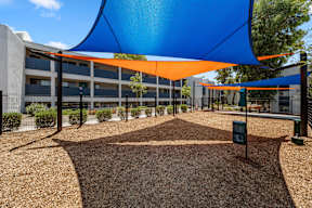 A playground with a blue and orange shade structure.
