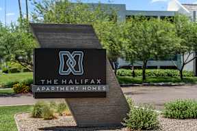 A sign for The Halifax Apartment Homes is displayed in front of a building.