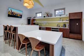 A modern kitchen with a white countertop and wooden chairs.