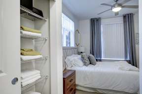 A white bedroom with a bed, dresser, and a white closet.