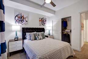 A bedroom with a bed, nightstand, and artwork on the wall.