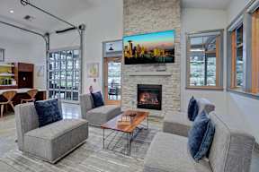 A living room with a stone fireplace and a large TV mounted above it.