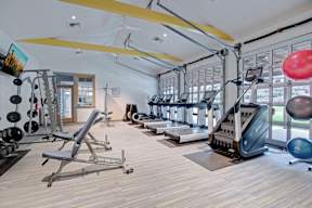 A gym with a variety of equipment including treadmills, weights, and exercise balls.