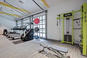 A gym with a variety of equipment including treadmills, weights, and a bench.