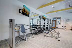 A gym with a variety of equipment including a weight machine, a bench press, and a squat rack.