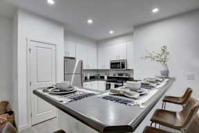 A modern kitchen with a large island and chairs.