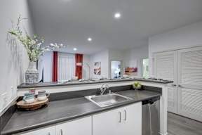 A modern kitchen with a grey countertop and white cabinets.