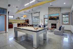 A billiard table is in the middle of a room with a fireplace and a painting on the wall.