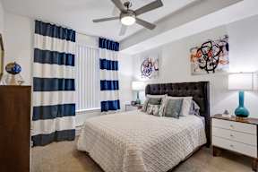 A bedroom with a bed, dresser, and a ceiling fan.