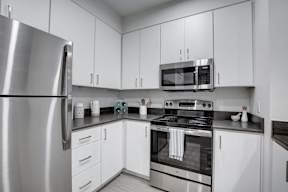 A modern kitchen with white cabinets and stainless steel appliances.