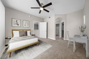 Large bedroom, carpet floors, ceiling fan with light, wall art, furnished model unit