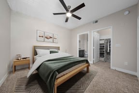 furnished bedroom with carpet floors, ceiling fan, wall art