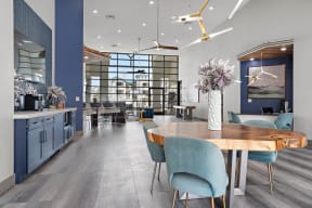 A clubhouse with table and chairs for sitting, ceiling lights, clubhouse kitchen area