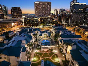 A cityscape at dusk with a lit-up building in the foreground.