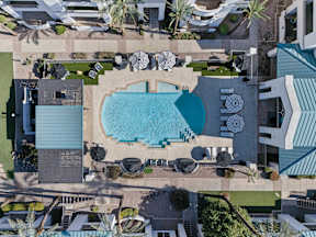 An aerial view of a pool surrounded by palm trees and lounge chairs.