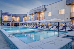 A large outdoor swimming pool with lounge chairs and umbrellas.