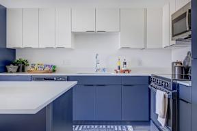 A kitchen with white countertops and blue cabinets.