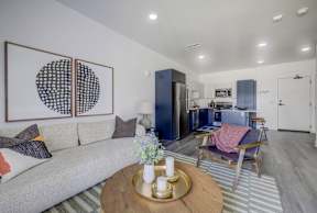 A modern living room with a grey couch, a coffee table, and a painting on the wall.