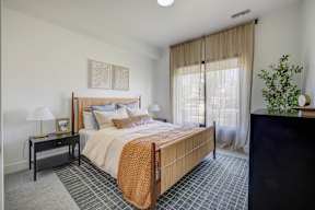 A bedroom with a large bed and a lamp on a nightstand.