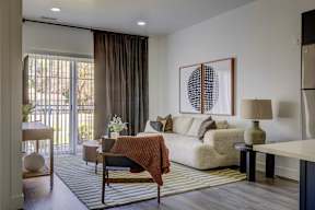 A modern living room with a white couch and a large abstract painting on the wall.