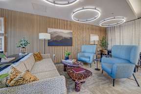 A living room with a grey couch, a blue chair, and a brown rug.