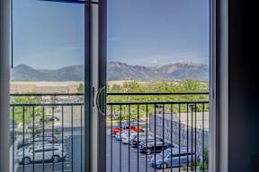 A view from a window looking out to a parking lot and mountains.