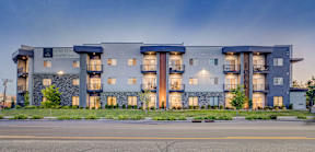 A modern apartment building with balconies and a stone facade.