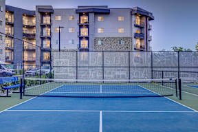 A tennis court is in front of a large building.